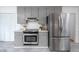 Well-lit kitchen featuring stainless steel appliances, updated gray cabinets, and tile backsplash at 5608 Ventura Dr, Durham, NC 27712