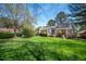 A beautiful, expansive backyard features a well-manicured lawn and mature trees for privacy and shade at 6 Preakness Dr, Durham, NC 27713