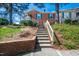 Brick home entrance with stairs leading to the door, accented by blue shutters and lush greenery at 6 Preakness Dr, Durham, NC 27713