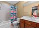 Bright bathroom features a shower with colorful floral shower curtain, wood vanity, and white sink at 6016 Glenthorne Dr, Raleigh, NC 27613