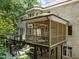 Rear exterior view of gray brick home featuring multiple decks, balconies, and a screened-in porch at 6016 Glenthorne Dr, Raleigh, NC 27613