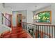 Upstairs hallway with wood floors, decorative railing, and window offering natural light at 6016 Glenthorne Dr, Raleigh, NC 27613