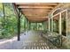 Covered brick patio with wood ceiling and supports, overlooking a private wooded backyard at 6016 Glenthorne Dr, Raleigh, NC 27613