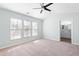 Spacious main bedroom with large windows, ceiling fan, plush carpet, and a glimpse into the ensuite bathroom at 602 Walnut Woods Dr # 62, Morrisville, NC 27560