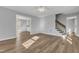 An empty living room featuring hardwood floors and gray walls, a view of the stairs, and a kitchen at 612 Miller Rd, Hillsborough, NC 27278