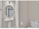 Chic half bathroom with a pedestal sink, modern toilet, and stylish round mirror, offering a functional space at 640 Newlyn Dr, Raleigh, NC 27606