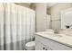 This bathroom offers a single sink with a white vanity, a shower with a striped curtain, and gray tile at 705 Marshall Farm St, Wake Forest, NC 27587