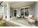 Inviting covered porch with brick base, cozy seating, and a decorative wreath on the front door at 705 Marshall Farm St, Wake Forest, NC 27587
