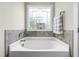 Serene bathroom with soaking tub, decorative tile, and a window for natural light at 81 N Lumina Ln, Clayton, NC 27527