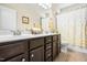 Bright bathroom featuring double sinks, dark wood cabinets, and a shower-tub combo at 81 N Lumina Ln, Clayton, NC 27527