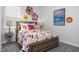 Bright bedroom with floral accents, a colorful comforter, and a bedside table with lamp at 88 Baldwin St, Lillington, NC 27546