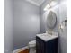 Stylish half-bath boasts a navy vanity, modern fixtures and decorative oval mirror at 107 Zaharis Cv, Raleigh, NC 27603