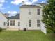 Backyard view shows green grass, a patio, and the exterior of the house under a cloudy blue sky at 1116 Silky Dogwood Trl, Apex, NC 27502