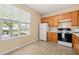 Eat-in kitchen has tile flooring, wood cabinets, white appliances, and a window overlooking the front yard at 1116 Silky Dogwood Trl, Apex, NC 27502