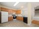Bright kitchen has wooden cabinets, white appliances, tile floors, and adjacent dining and staircase areas at 1116 Silky Dogwood Trl, Apex, NC 27502
