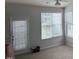 Bright living room features neutral walls, carpet, and natural light from the window and glass door at 1116 Silky Dogwood Trl, Apex, NC 27502
