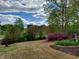 Lush backyard featuring flowering azaleas and manicured landscaping under a cloudy sky at 117 Linwood Ln, Clayton, NC 27527