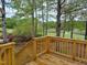 Wooden deck railing overlooking mature trees and a lake and golf course view at 117 Linwood Ln, Clayton, NC 27527