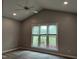 This vaulted bedroom features a ceiling fan, neutral paint, and large windows overlooking the backyard at 117 Linwood Ln, Clayton, NC 27527