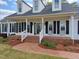 Inviting front porch with classic white railings, brick steps, and decorative chairs create a welcoming entrance at 117 Linwood Ln, Clayton, NC 27527