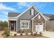 Charming two-story home featuring gray siding, stone accents, a quaint front porch, and an attached garage at 1243 White Flint Cir, Durham, NC 27703