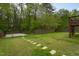 Lush backyard with mature trees, a concrete pad, and stone pavers at 136 Ashlyn Ridge Dr, Garner, NC 27529