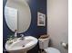 Stylish powder room with a round mirror, pedestal sink, and blue accent wall at 136 Ashlyn Ridge Dr, Garner, NC 27529