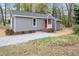 Charming home showcasing a red front door, gray siding, and gravel driveway, nestled within a lush green landscape at 206 Woods Run, Knightdale, NC 27545