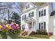 Charming white home with black shutters and a welcoming front porch with decorative flowers at 2061 Carriage Way, Chapel Hill, NC 27517