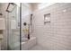 Closeup of a shower with a rain shower head, bench and a decorative plant, set against white subway tile at 2075 Toad Hollow Trl, Apex, NC 27502