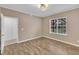 Neutral bedroom with wood-look flooring, trim, light fixture, and a window at 208 Chandler Chase Ct, Morrisville, NC 27560