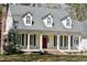 Classic home with a columned front porch and red door is complemented by mature landscaping and dormer windows at 218 Keith Hills Rd, Lillington, NC 27546