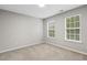 Neutral bedroom featuring two windows allowing for natural light, complemented by carpeted floors at 2310 Nutting Ln, Apex, NC 27523
