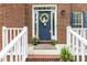 Charming front porch with white railing, red brick steps and a welcoming blue door with floral decorations at 2310 Nutting Ln, Apex, NC 27523