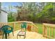 View of the deck with green chairs, a small table, and a view of the green lawn and treeline at 2603 Brogden Rd, Creedmoor, NC 27522