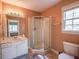 Well-lit bathroom features a corner shower, single sink vanity, and peach walls at 2932 Candlehurst Ln, Raleigh, NC 27616