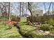 Backyard view featuring a red bridge, mature trees, and patio furniture, creating a tranquil outdoor space at 303 N Guthrie Ave, Durham, NC 27703
