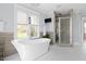 Bright bathroom featuring a soaking tub, walk-in shower, and view through the window at 303 N Guthrie Ave, Durham, NC 27703