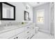 Bright bathroom featuring double sinks with a marble countertop, a white cabinet, and a hexagon-tiled floor at 303 N Guthrie Ave, Durham, NC 27703