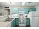 Bright kitchen featuring stainless steel sink, white appliances, and blue-green cabinetry at 3050 Trailwood Pines Ln # 101, Raleigh, NC 27603