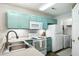 Bright kitchen featuring stainless steel sink, white appliances, and blue-green cabinetry at 3050 Trailwood Pines Ln # 101, Raleigh, NC 27603
