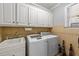 Functional laundry room featuring a front-load washer/dryer, ample cabinet space, and a utility sink at 3424 English Cir, Willow Springs, NC 27592
