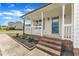 Charming covered front porch featuring brick steps, white railing, and a stylish teal front door at 3533 N Way Dr, Zebulon, NC 27597