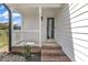 Covered front porch with brick steps, white railing, and a storm door at 3533 N Way Dr, Zebulon, NC 27597