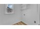 Bright laundry room featuring wood floors, convenient hookups, window, and overhead shelving at 3533 N Way Dr, Zebulon, NC 27597