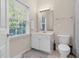 Bright bathroom featuring a vanity with storage, a large window, and a toilet with standard fixtures at 4 Scottish Ln, Durham, NC 27707