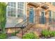 Inviting front porch with brick steps, black iron railing, and a teal-painted front door with wreath at 4 Scottish Ln, Durham, NC 27707
