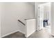 Neutral hallway featuring carpeted floors, a wooden handrail, and an open doorway at 4 Scottish Ln, Durham, NC 27707