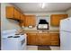 Well-lit kitchen with wood cabinets, white appliances, and charming wallpaper at 4308 James Rd, Raleigh, NC 27616