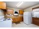 Functional kitchen with wood cabinets, white appliances, and patterned wallpaper at 4308 James Rd, Raleigh, NC 27616